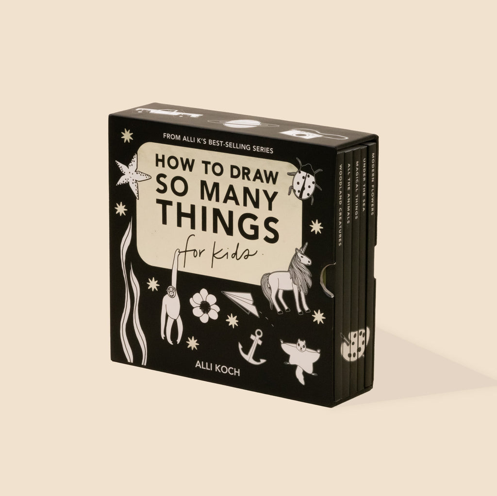 A boxed children's art/activity book titled "How to Draw So Many Things for Kids" by Alli Koch, shown standing upright on a warm beige background. The box is black with cream panels and white line drawings of animals, stars, flowers, and abstract shapes.