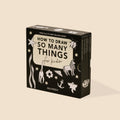 A boxed children's art/activity book titled "How to Draw So Many Things for Kids" by Alli Koch, shown standing upright on a warm beige background. The box is black with cream panels and white line drawings of animals, stars, flowers, and abstract shapes.