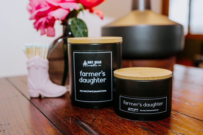 Two 'farmer's daughter' candles on a wooden surface with a blurred background