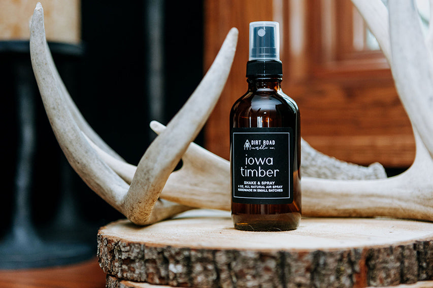 Bottle of 'Iowa Timber' on a wooden surface with antlers in the background
