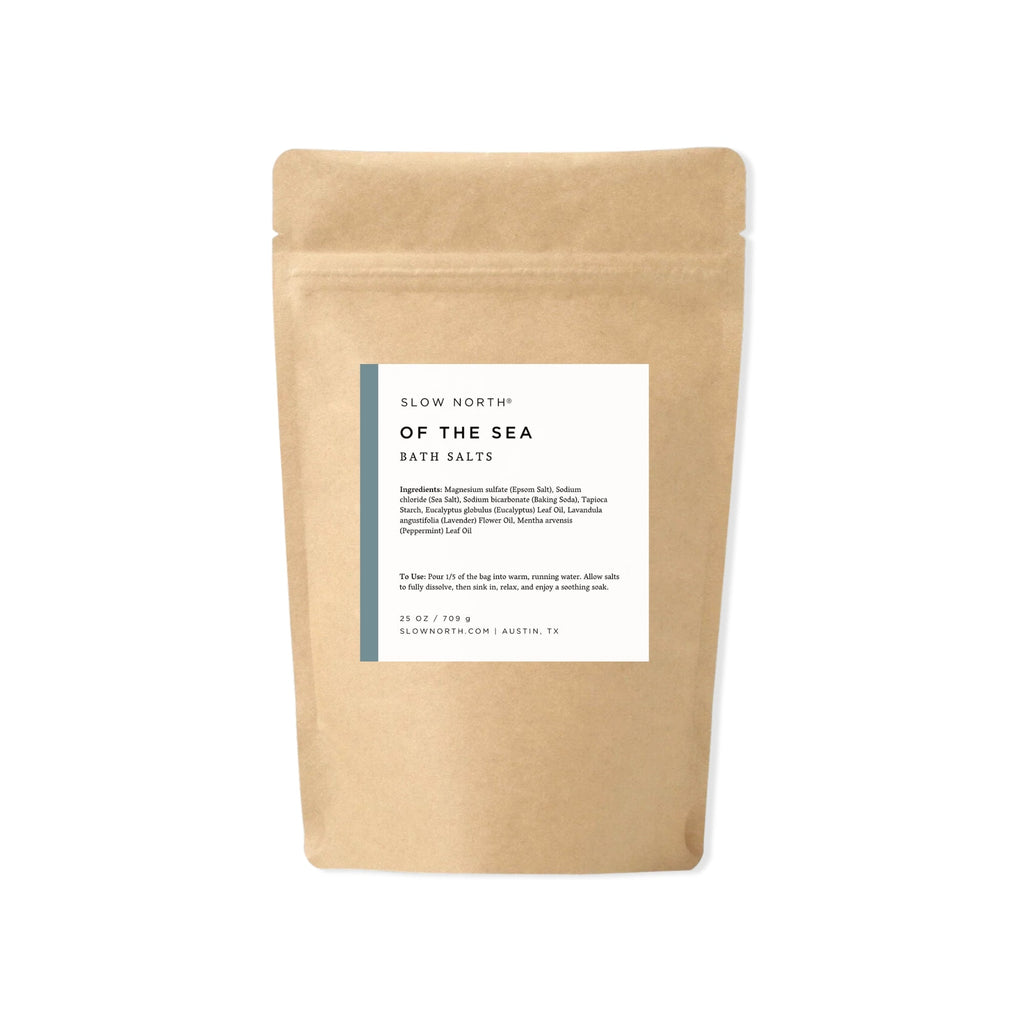 Kraft paper packaging with a label for 'Of the Sea' bath salts on a white background