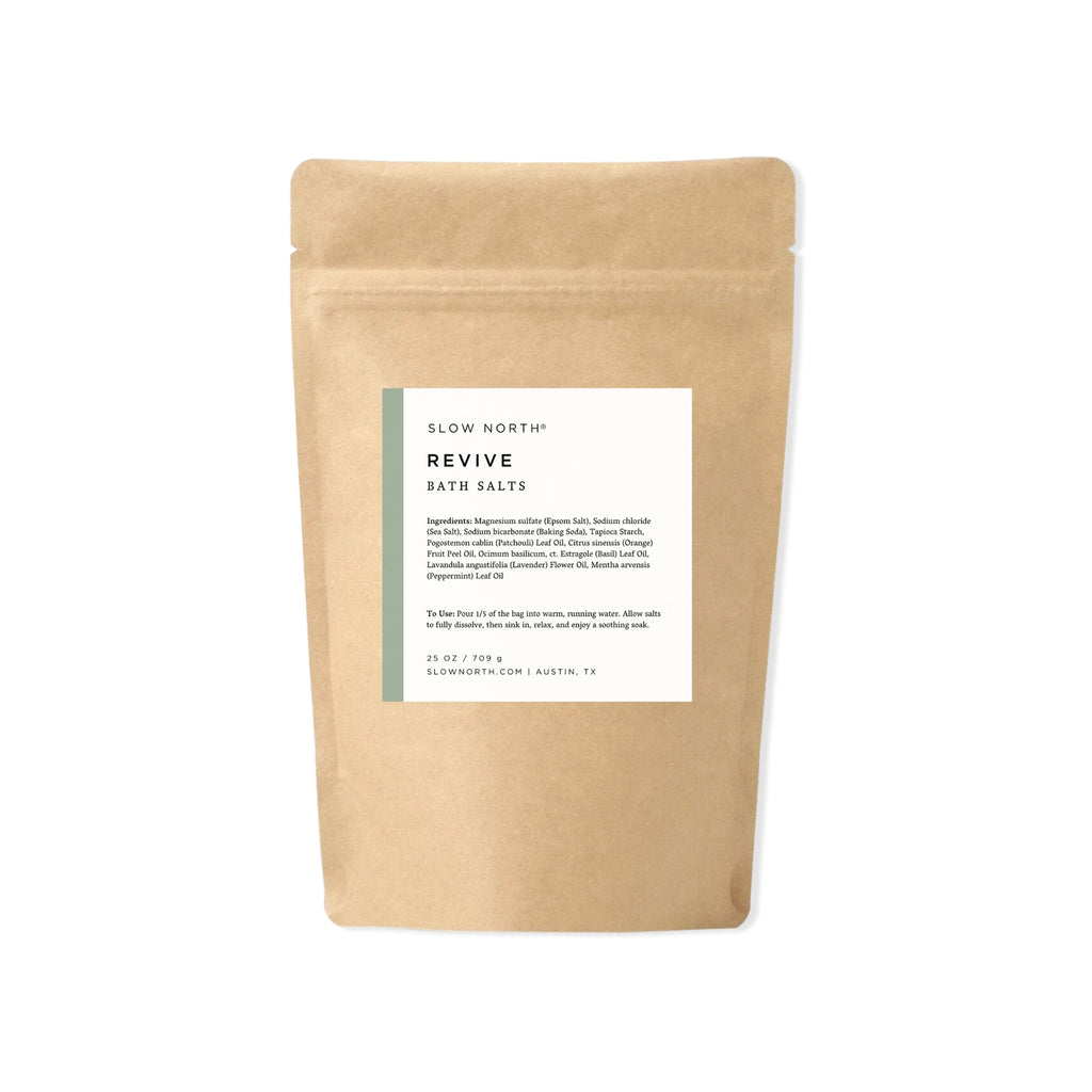 Kraft paper packaging with a label for 'Revive' bath salts from Slow North on a white background