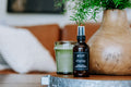 Shiplap bottle on a surface with a candle and vase in the background