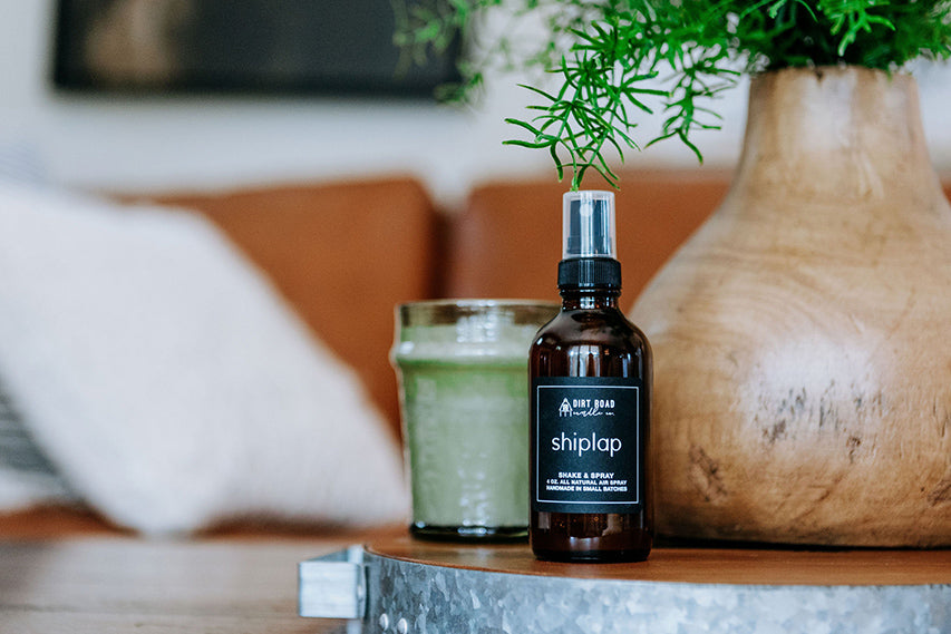 Shiplap bottle on a surface with a candle and vase in the background