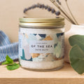 Jar of 'Of the Sea' bath salts with a decorative label on a wooden surface.