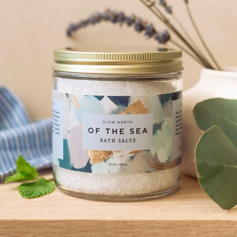 Jar of 'Of the Sea' bath salts with a decorative label on a wooden surface.